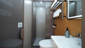A modern bathroom with a glass-enclosed shower, a white toilet, and a sink with a mirror above. - Dongjing Hotel (Shanghai Shanda College Branch) (Shanghai)
