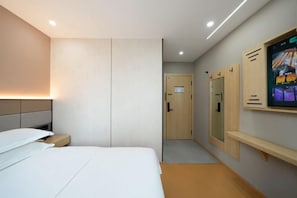 A hotel room with a bed, a bedside table, a TV mounted on the wall, and a door leading to the bathroom. - Dongjing Hotel (Shanghai Shanda College Branch) (Shanghai)