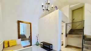 A spacious hallway with a staircase, a mirror, a bench, and a vase with dried plants. - YourHome - Antico Casale Sorrentino (Meta)
