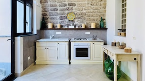 A kitchen with a stone wall, a window, and a built-in oven. - YourHome - Antico Casale Sorrentino (Meta)