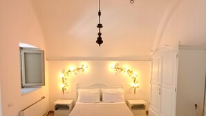 A bedroom with a bed, nightstands, a hanging light fixture, a wardrobe, and a mirror on the wall. - YourHome - Antico Casale Sorrentino (Meta)