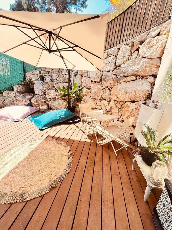 A wooden deck with a hammock, a table, and chairs under a canopy.