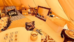 A cozy interior of a tent with a bed, pillows, a table with decorative items, and a mirror. - Eco-lodge yurt with luxury Jacuzzi at C&C for ADULTS only (Cantaron)