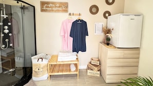 A hotel room with a glass shower, wooden bench, two clothes hangers with garments, a wooden cabinet, and a refrigerator. - Eco-lodge yurt with luxury Jacuzzi at C&C for ADULTS only (Cantaron)
