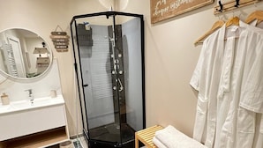 A modern bathroom with a glass-enclosed shower, a vanity with a mirror, and a wooden bench with towels. - Eco-lodge yurt with luxury Jacuzzi at C&C for ADULTS only (Cantaron)
