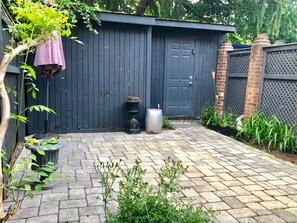 A garden with a paved walkway, a dark wooden shed, and a brick wall. - 5 Blocks to US Capitol, Renovated 1895 Capitol Hill Victorian (Washington)