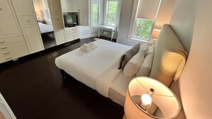 Quarto com cama grande, televisão, escrivaninha e janela.