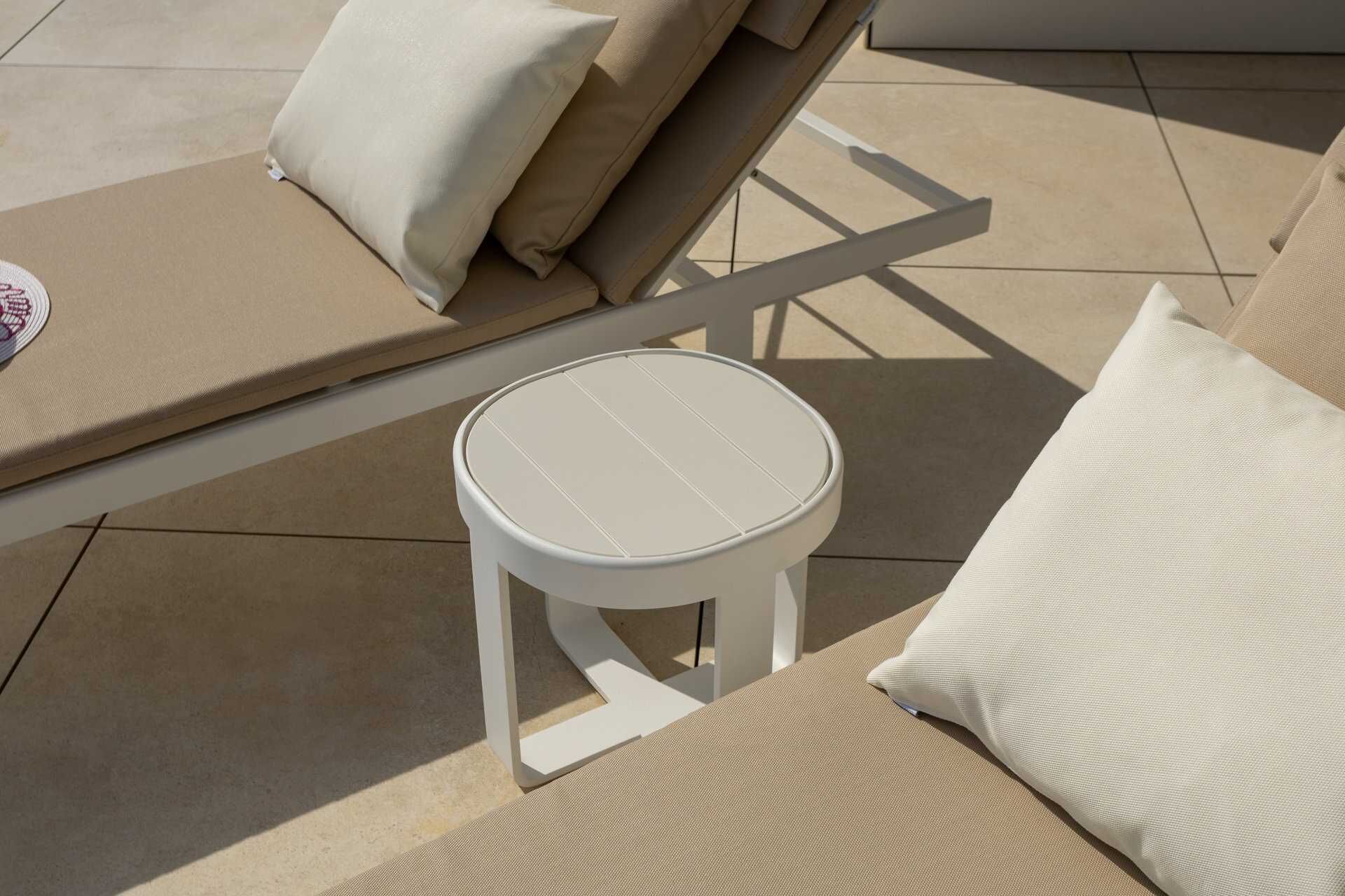 A sunlit outdoor seating area with a round table and lounge chairs.