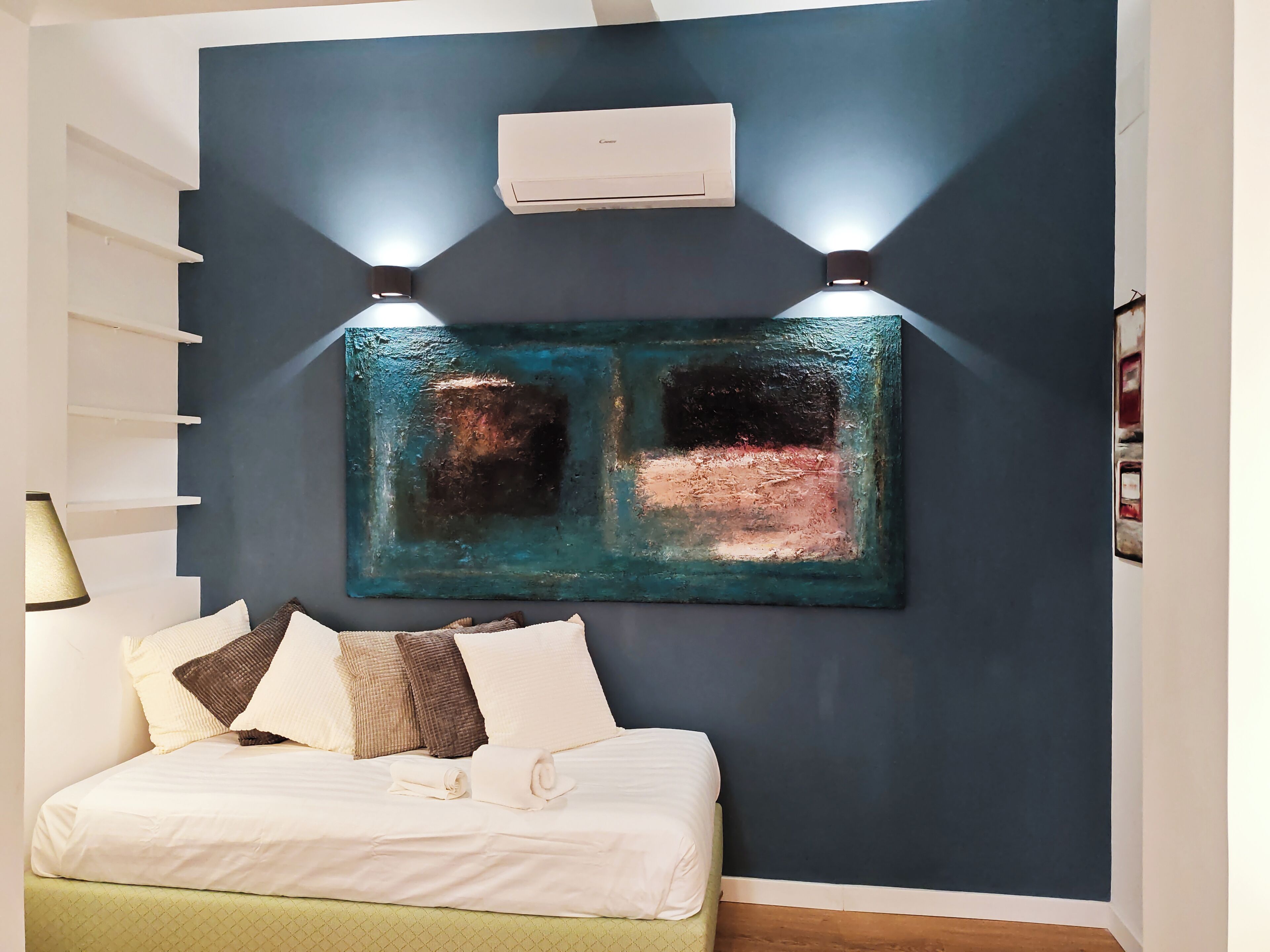 Een slaapkamer met een bed, een wandairconditioner en twee wandlampen.