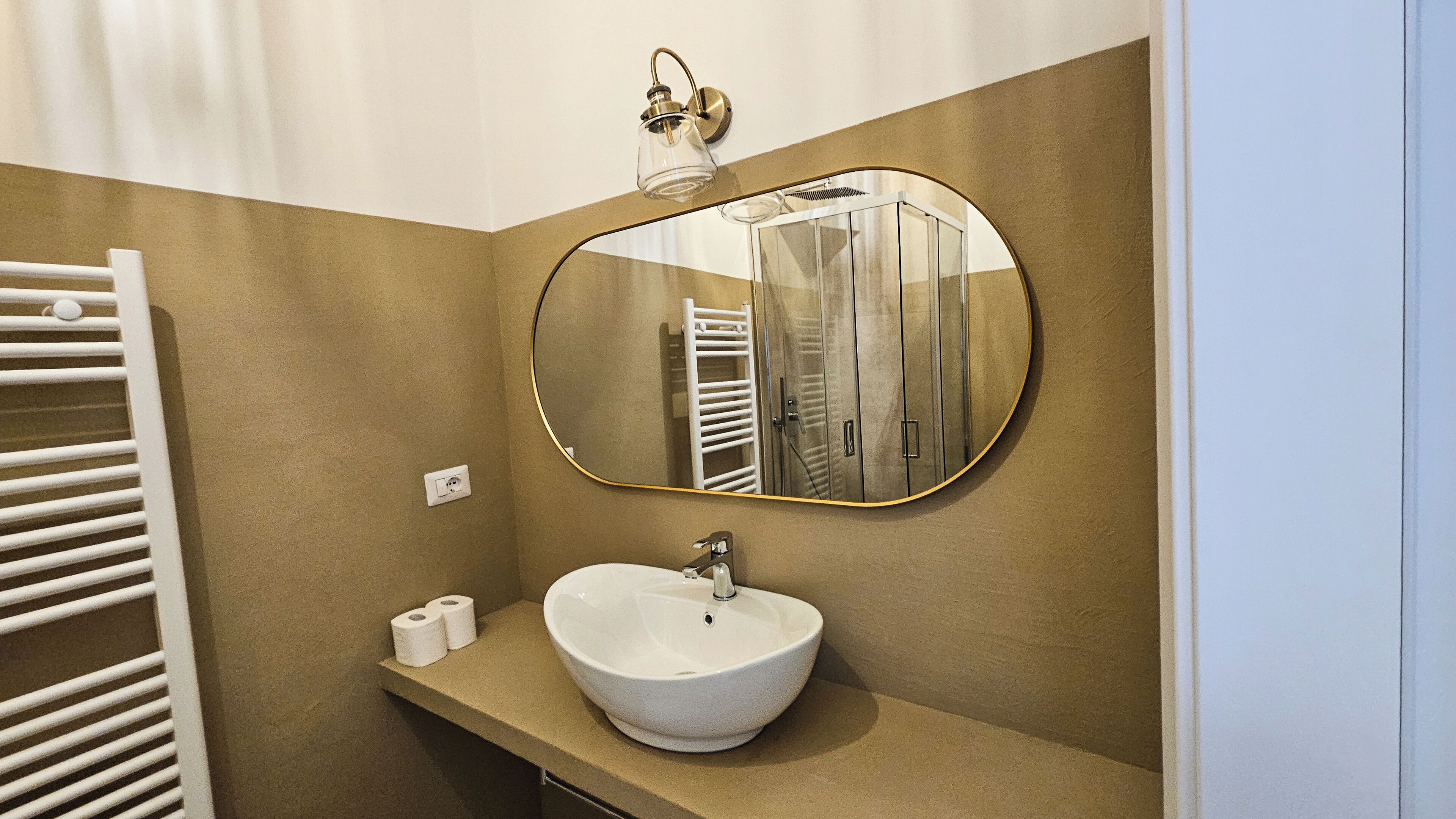 A bathroom with a round mirror, a white sink, and a towel rack.