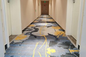 A hallway with a patterned carpet, doors on either side, and a visible exit sign at the end. - Ruisite Hotel, Luxian County (Jing County)