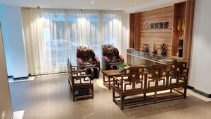 Una sala de estar moderna con un sofá, dos sillones de masaje, una mesa de centro de madera y un estante decorativo con objetos.