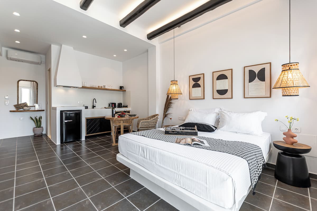 A modern hotel room with a large bed, a small kitchenette, and a dining area.