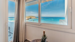 A room with a view of the sea through large windows, a curtain, and a small table with a pineapple. - Fleria Seaview Suites (Naxos)