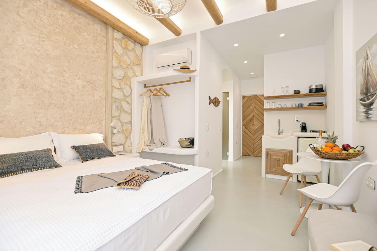 A modern hotel room with a large bed, a small kitchenette, and a dining area.