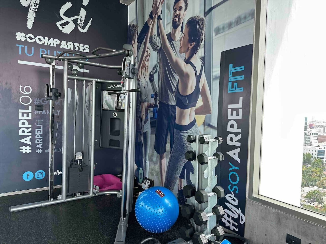 Une salle de sport équipée de matériel d’exercice, avec un ballon d’exercice bleu et une grande affiche représentant une femme en train de faire de l’exercice.