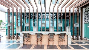 Un espace bar moderne avec un sol à motifs en chevrons, des poutres en bois et une vue sur la ville grâce à de grandes fenêtres.