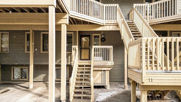 A two-story building with a wooden deck and a staircase. - Golden Summit | Air Hockey | Wood Fireplace | Pets (Radium Hot Springs)