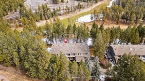 A lodge with multiple buildings surrounded by dense forest, a river, and a snow-covered area. - Golden Summit | Air Hockey | Wood Fireplace | Pets (Radium Hot Springs)