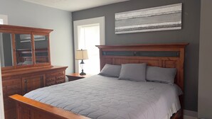 Un dormitorio con una cama grande, cómoda de madera y una lámpara.