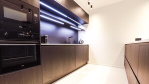 A modern kitchen with built-in appliances, wooden cabinetry, and a sleek countertop. - Apartment Near Durbuy Old Town & Golf (Durbuy)