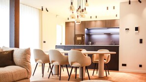 A modern living room with a sofa, chairs, and a coffee table. There is a kitchen area with a dining table and chairs. - Apartment Near Durbuy Old Town & Golf (Durbuy)