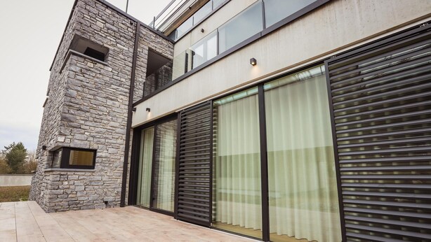A modern building with a stone facade, large sliding glass doors, and a flat roof. - Apartment Near Durbuy Old Town & Golf (Durbuy)