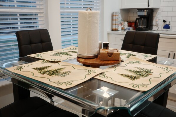 A dining table with a glass top, four chairs, and a candle centerpiece. - Lindo Lanier Cottage in Gainesville (Gainesville)