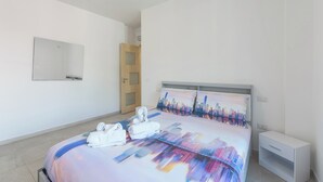 A modern hotel room with a large bed, a cityscape bedspread, a bedside table, and a door. - Ideal for exploring the Amalfi Coast, Capri, Sorrento, Pompeii, Paestum and more (Salerno)