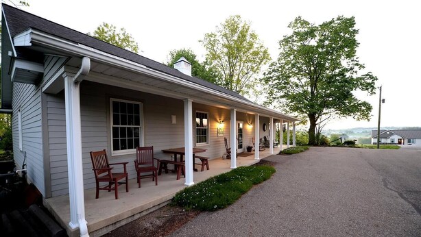 A house with a covered porch, outdoor seating, and a view of the landscape.