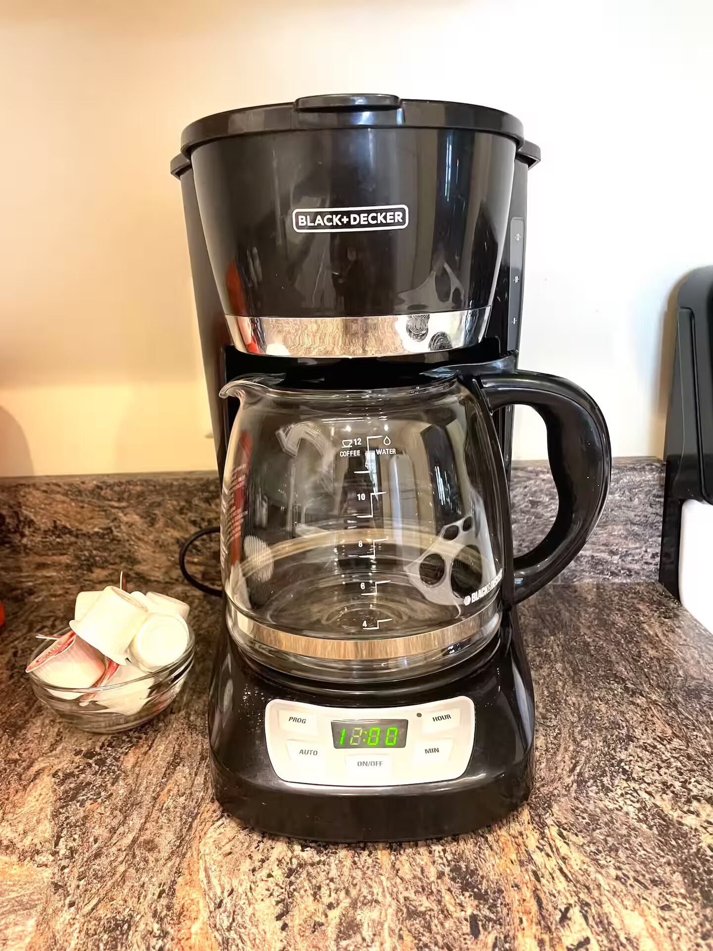A BLACK+DECKER coffee maker with a digital display, a glass carafe, and a timer.