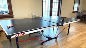 A ping pong table with wheels and a red handle, labeled 'STIGA'.