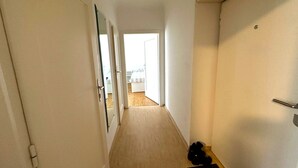A narrow hallway with a wooden floor, a black mat at the entrance, and a door on the right. - Apartment Near Schonbrunn Palace Vienna (Vienna)