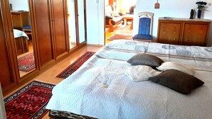 A bedroom with a large bed, wooden wardrobe, and a small desk with a chair. - Beautiful ground floor apartment 65sqm, fully equipped with beautiful garden and terrace (Cloppenburg)