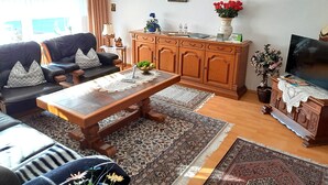 A living room with a sofa, coffee table, wooden cabinet, TV, and decorative items. - Beautiful ground floor apartment 65sqm, fully equipped with beautiful garden and terrace (Cloppenburg)