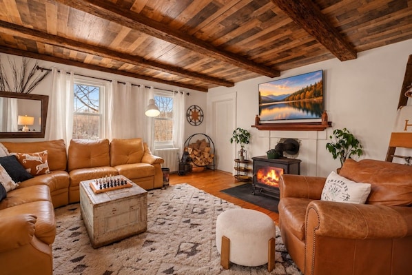A cozy living room with leather sofas, a fireplace, and a large painting on the wall.