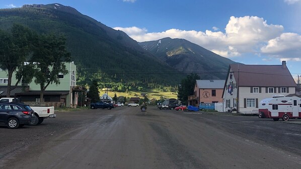 A road leading to a small town with buildings and a mountain in the background.