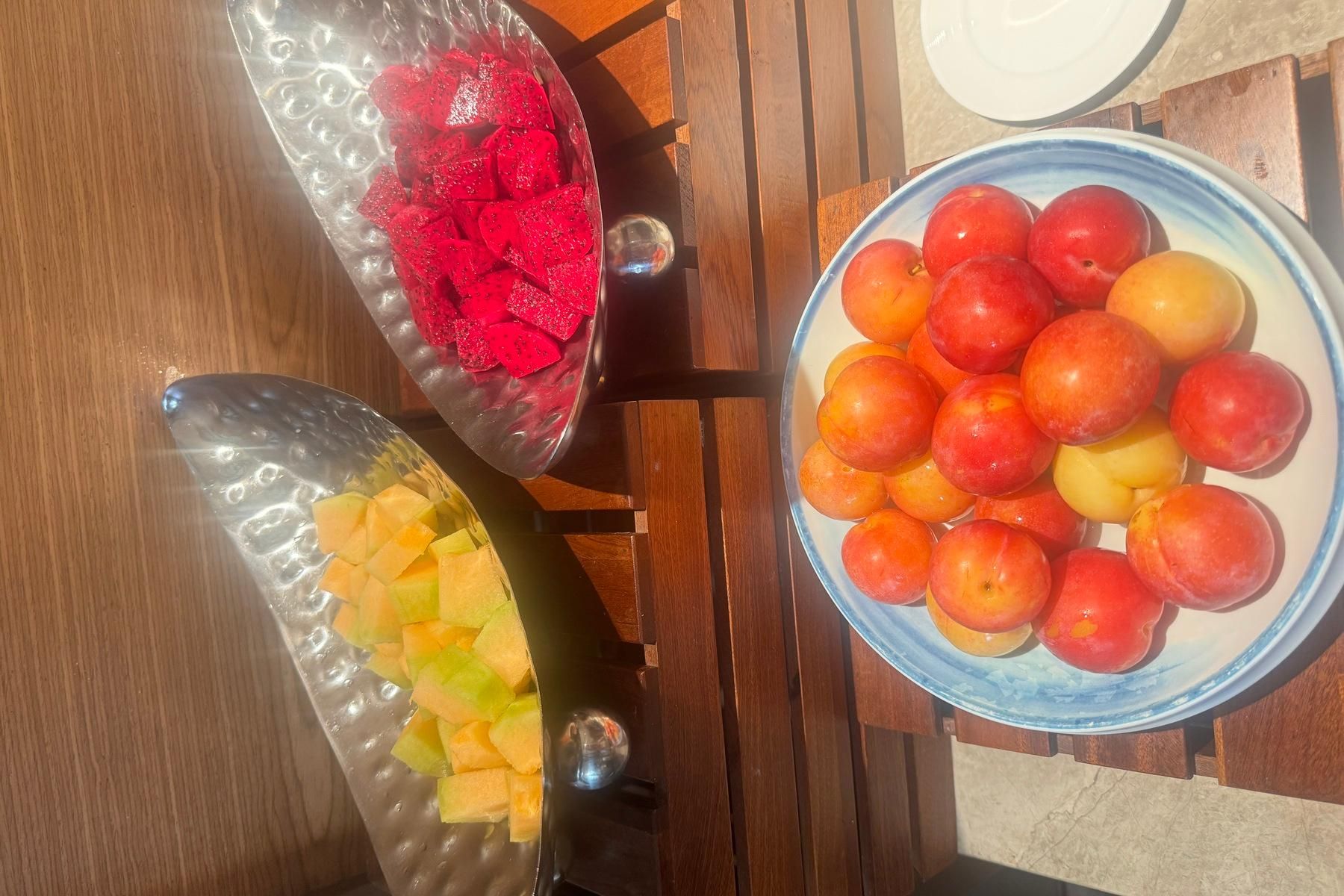 A table with three glass bowls containing fruits.