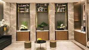 Een modern interieur met een bank, een ronde tafel met een vaas en ingebouwde boekenkasten met planten.