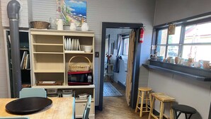 A cozy kitchen with wooden flooring, a dining table with chairs, a bookshelf, and a window with a view of the street. - #1 Guest House 2Bd 2 Bath Pet Friendly Across from Spa (Silverton)