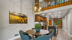 Une cuisine moderne avec des meubles en bois, un îlot central et un coin repas comprenant une table ronde et des chaises.