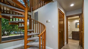 Un escalier en colimaçon en bois, dont les marches sont recouvertes de moquette, mène au deuxième étage.