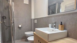 Une salle de bain moderne avec un grand lavabo, des toilettes et une douche.