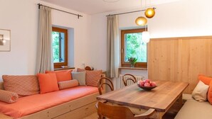 Une pièce chaleureuse avec un canapé en bois, une table à manger et deux fenêtres avec des rideaux.