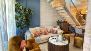 Una sala de estar moderna con un sofá, sillones, una mesita de centro y una escalera.