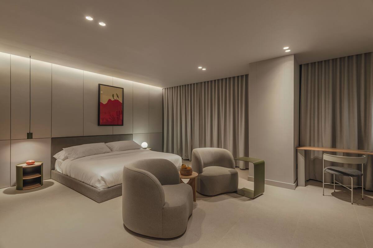 Un dormitorio moderno con una cama grande, dos sillones, un escritorio y una mesita.