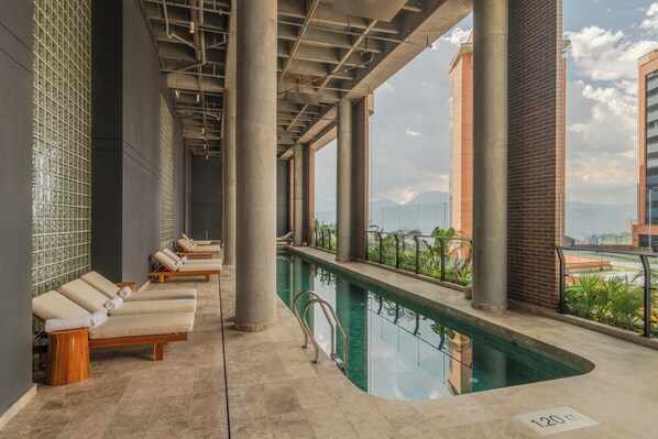 A pool area with lounge chairs, a clear view of the cityscape, and a sign indicating the pool's depth. - Wake BioHotel, a Member of Design Hotels (Medellín)