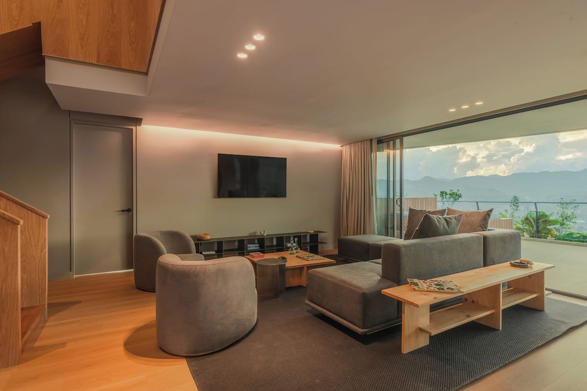 Una sala de estar moderna con sofá, reposapiés, mesa de centro y televisión.