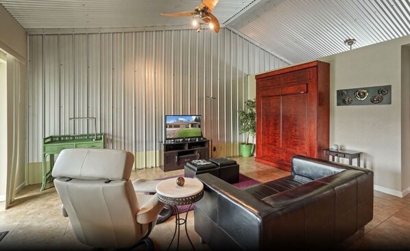 A modern living room with a sofa, armchair, and entertainment unit. - Escape to our Lakeside Loft (Galt)