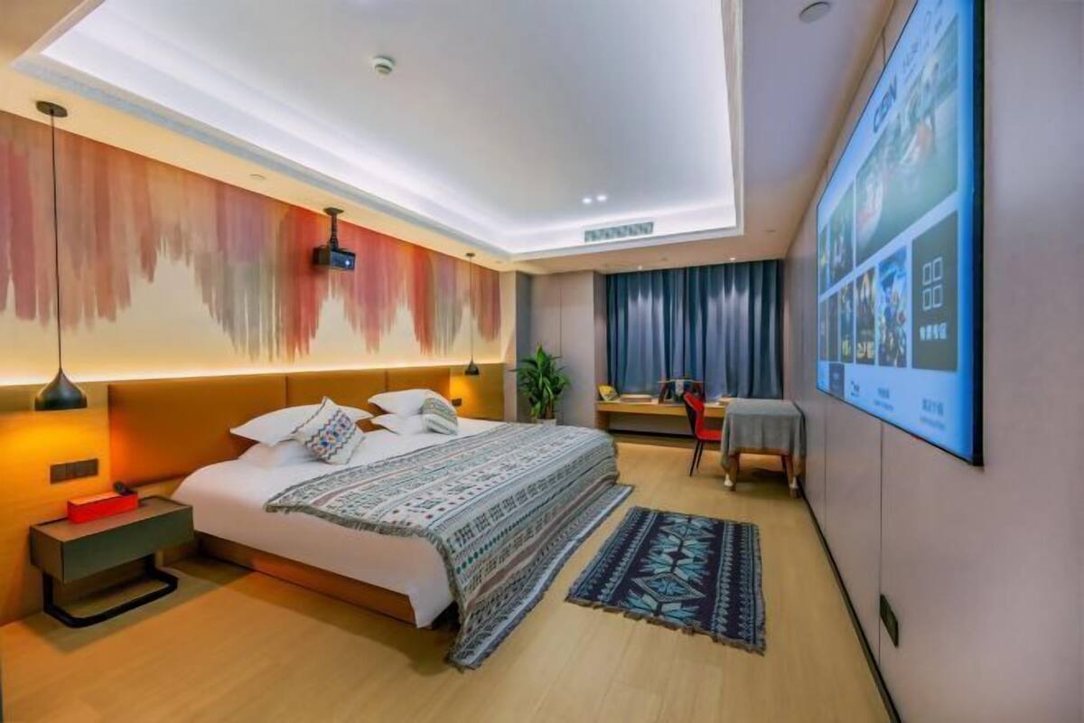 Una habitación de hotel moderna con una cama grande, un escritorio, una silla, un televisor y una lámpara en el techo.